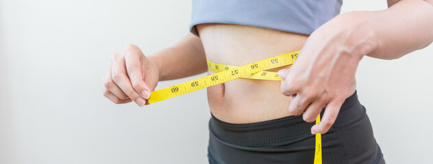 Workout, Slim asian young woman, girl standing, hand in measuring tape around waist her in fit sportswear on white background. Sport strong person in gym fitness for wellbeing, health and copy space.