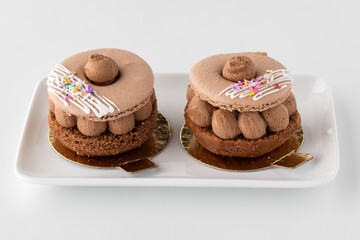Two mini chocolate macaroon cakes on a small serving dish.