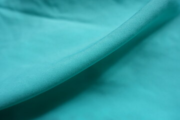 Diagonal fold on thin bluish green chiffon fabric