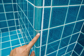 Tiled pool. The man hand while using spacer for installing tiles. construction work.Construction...