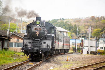 Fototapeta na wymiar 煙突から煙を棚引かせ出発を待つ蒸気機関車の牽引する列車