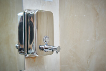 Metal bathroom dispenser for soap or disinfectant.