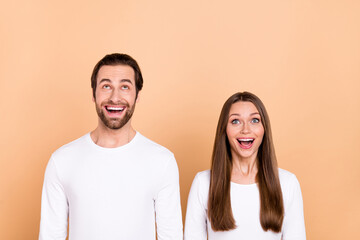 Portrait of attractive cheerful amazed trendy brown-haired spouses look up copy space wow isolated over beige pastel color background