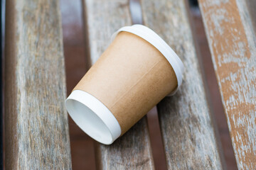 Glass for coffee or tea to go on a brown wooden bench in the winter.