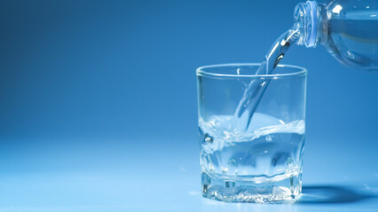 studio shot Clean drinking water poured into glass and natural blue background. healthy drinking water concept
