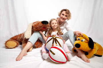 Nice mom and beautiful blonde daughter in room of the studio durin spring photo shoot before easter. Happy girl and woman together