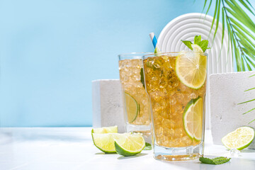 Cuba Libre, long island iced tea cocktail with strong alcohol drink, cola, lime and ice in two glass, cold longdrink mocktail on light blue tiled background