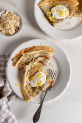 Crepes, thin pancakes with poppy seeds, lemon and sour cream on marble background. Healthy breakfast in sunny morning .