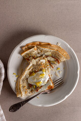 Crepes, thin pancakes with poppy seeds and sour cream on brown background. 