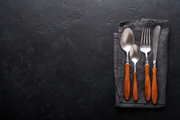 Vintage silverware. Rustic vintage set of wooden spoon and fork on black background. Top view. Mock...