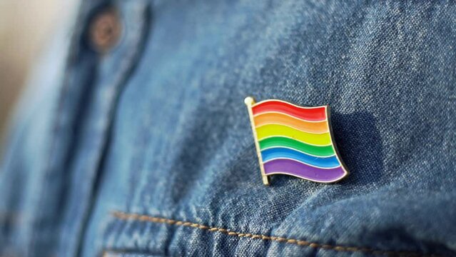 Close up of LGBT icon in the form of a flag is pinned on blue jeans jacket. Support for a free parade. LGBT community.