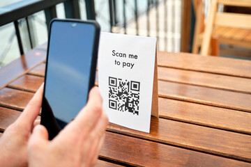 Unrecognizable client scanning a QR code to pay cashless, contactless