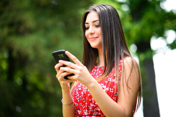 Young beautiful woman using her smartphone in the park, outdoor