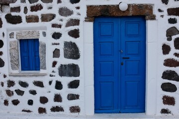 A traditional made house with a blue door and blue shutters in Santorini greece