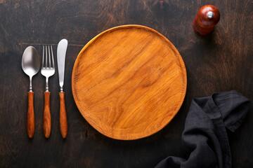 Vintage silverware. Rustic vintage set of wooden spoon and fork on wooden platter on black wooden background. Empty dishes. Top view. Mock up.