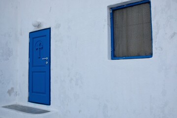 Naklejka na ściany i meble View of a traditional blue door and a window of a white orthodox chapel in Santorini 