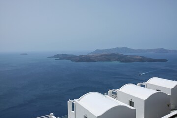 View of  luxury villas with balconies  and a ferry boat next to the volcano of Santorini 