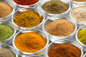 Glass bowls with variation of colorful powder herbs full frame as background