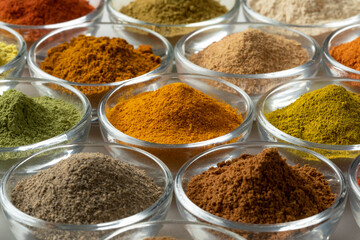 Glass bowls with variation of colorful powder herbs full frame as background