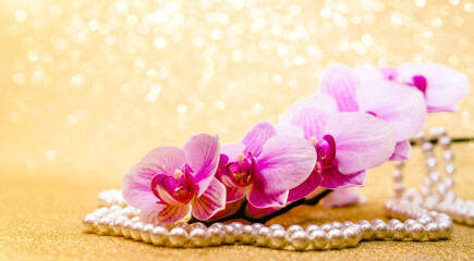 Fototapeta na wymiar purple Orchid and pearl necklace on a shiny gold background 
