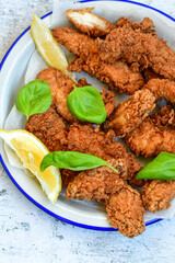 
 Crispy  deep fried   chicken strips and wedges potato. Breaded  with cornflakes chicken  breast fillets  with chilly peppers and fresh   basil on wooden rustic background