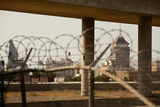 Barbed wire and a concrete overpass frame the downtown skyline of Fresno, California, USA.