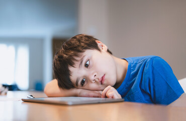 School kid using tablet for homework, Child bored face lying head down looking out deep in thought,...