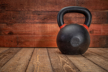 Fototapeta na wymiar iron kettlebell on a rustic wood background with a copy space, home gym fitness concept