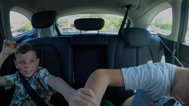 Two distracting young brats play fighting in the back seat of a car. Sibling rivalry in slow motion.