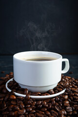 Cup of coffee with coffee beans on dark background. Mug of hot drink coffee