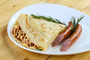 Pancake with sliced sausage and mustard
