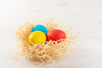 Easter painted eggs in a nest on a wooden background.