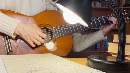 Close up of female hands playing guitar. Woman studying to play guitar. Hobby and leisure activities