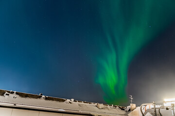 Beautiful northern light (or aurora borealis) phenomenon over the city of Narvik in Northern Norway. Stunning green light resulting from solar wind interacting with earth's atmosphere.