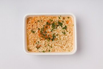 instant noodles in a container with water, vegetables and hot spices on a white background. fast food concept