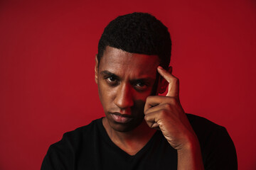 Young black man pointing finger at his temple and looking at camera