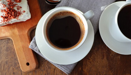 Red velvet cake and two coffee cups for breakfast on wooden background. Tasty dessert. Close up