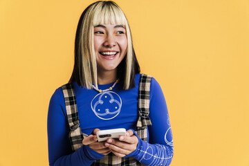 Asian girl with piercing smiling and using mobile phone