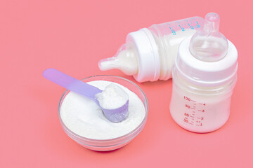 Baby milk bottles with mixture and baby milk formula in the jar on pink background. Powdered milk...