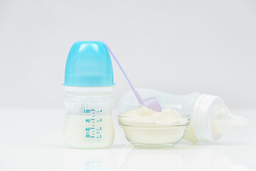 Baby milk bottles with mixture and baby milk formula in the jar on pink background. Powdered milk dairy food for newborn