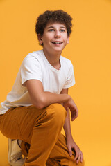 White curly boy wearing suit smiling while crouching