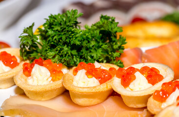 Seafood appetizers. Sandwiches with a game, a tartlet appetizer with sauce and red caviar, sliced red salmon fish and cream sauce with scrambled eggs.