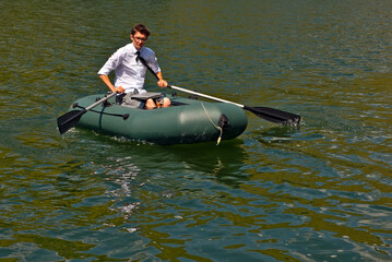 A man in a white shirt on an inflatable boat. Businessman with laptop resting on the lake. The concept of remote work, leisure and freelance.