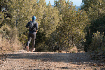 Man trail running in the mountains on a path.