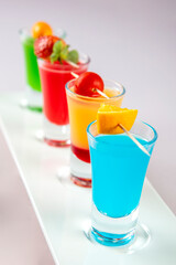 Variety of colorful green blue yellow red and white beautiful alcohol sweet shooters shots cocktail fresh beverage in small glasses. Alcoholic tropical cocktails isolated on white background.