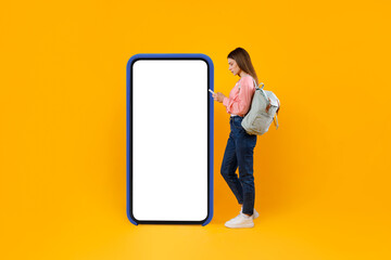 Woman Tourist Using Smartphone Standing Near Big Cellphone, Yellow Background
