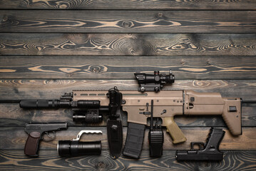 Airsoft weapon and equipment on the wooden flat lay background with copy space.