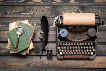 Retro style typewriter, quill pen and books on the wooden desk table background. Writer table.