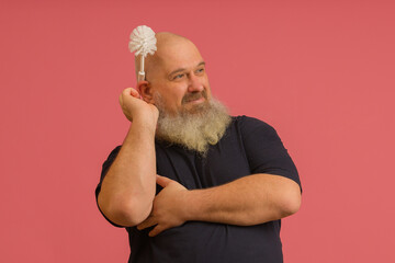 bearded man decorated his head with a toilet brush on a pink background