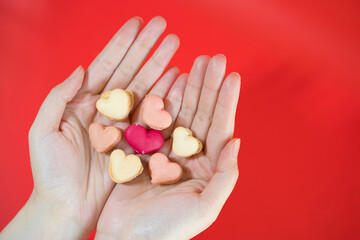 flat lay heart shape of macarons on hand with red background